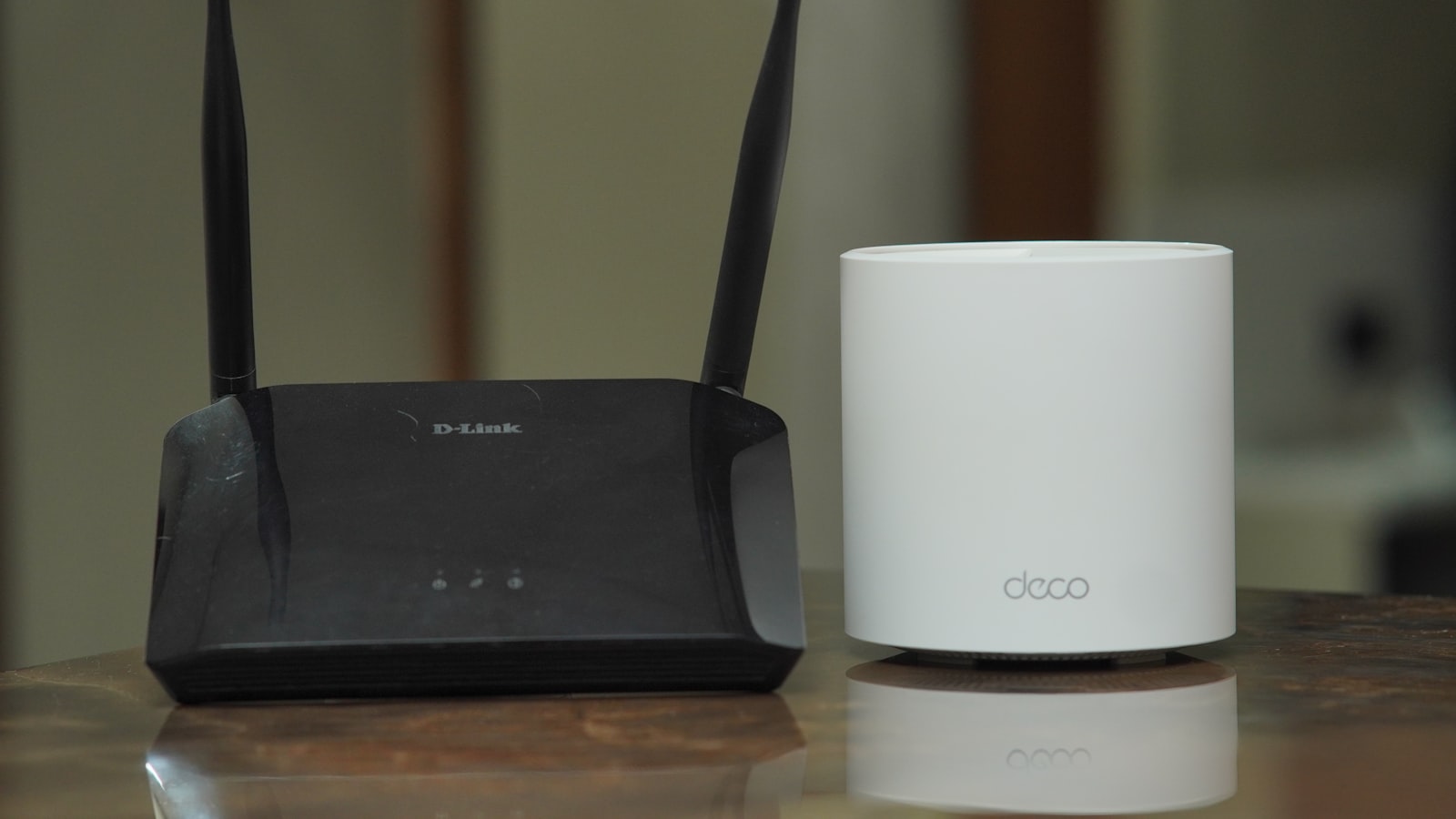 An older router beside a modern mesh Wi-Fi node