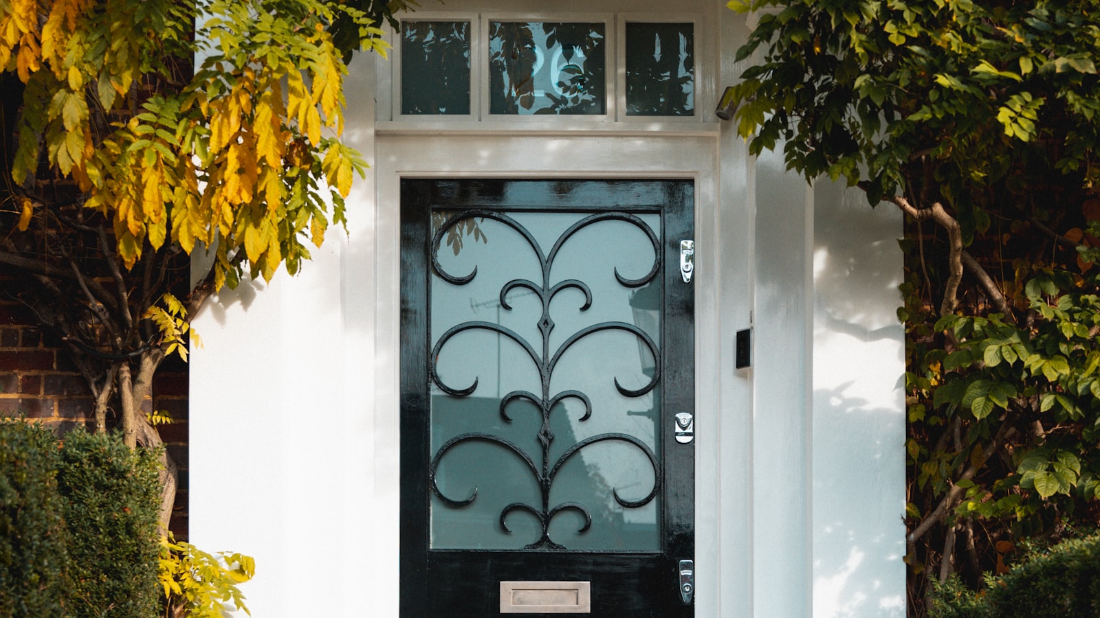 A black front door with decorative glass, seen from a porch