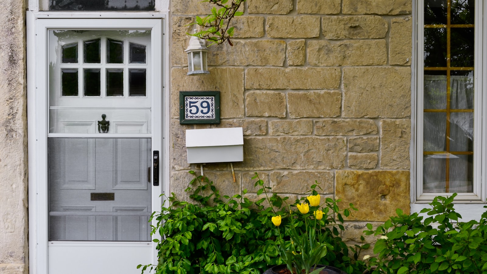 A residential front door with a house number and a letterbox on a stone wall