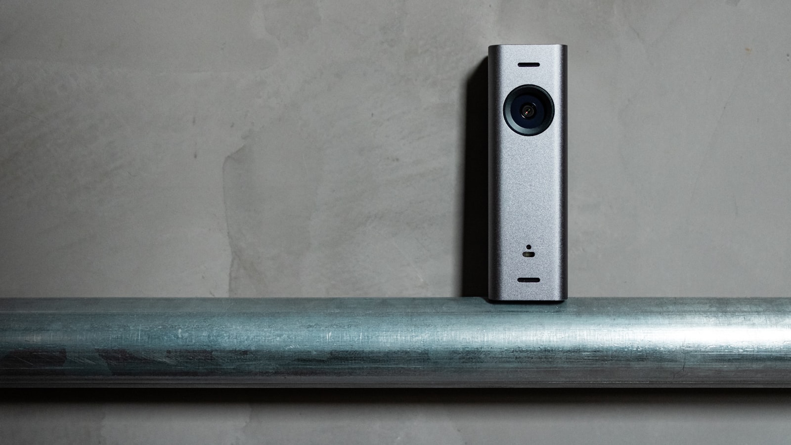 A small indoor security camera on a metal rail
