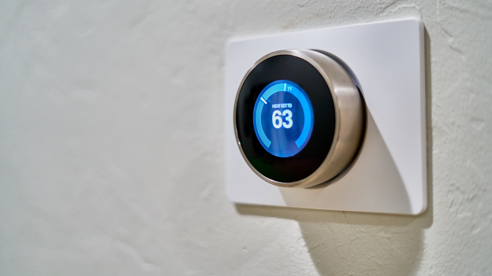 A round smart thermostat on a wall, set to heat