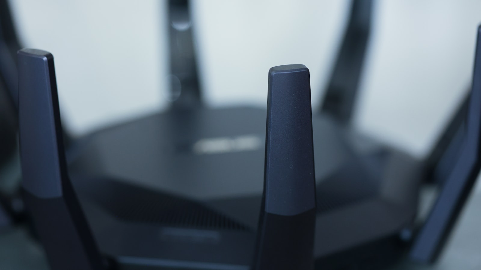 A modern black Wi-Fi router with its antennas raised